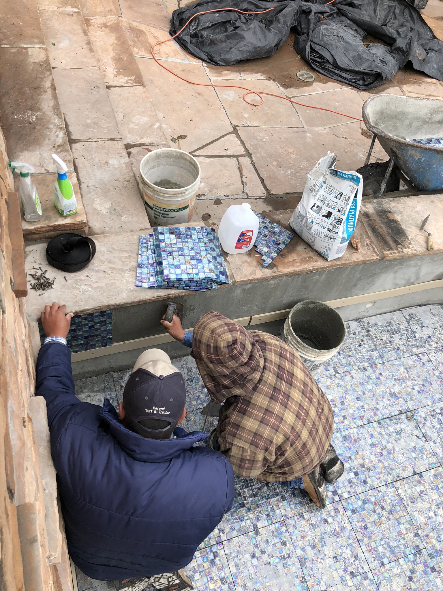 Our crews removed old glass tile that dated back to the 1960s. Now that's an old swimming pool! To replace it, we purchased some beautiful 1" Mosaic Glass Tile & set it using gray thinset & grout. Our teams are very detail oriented and take our time setting these beautiful tiles to produce an even and gorgeous look!