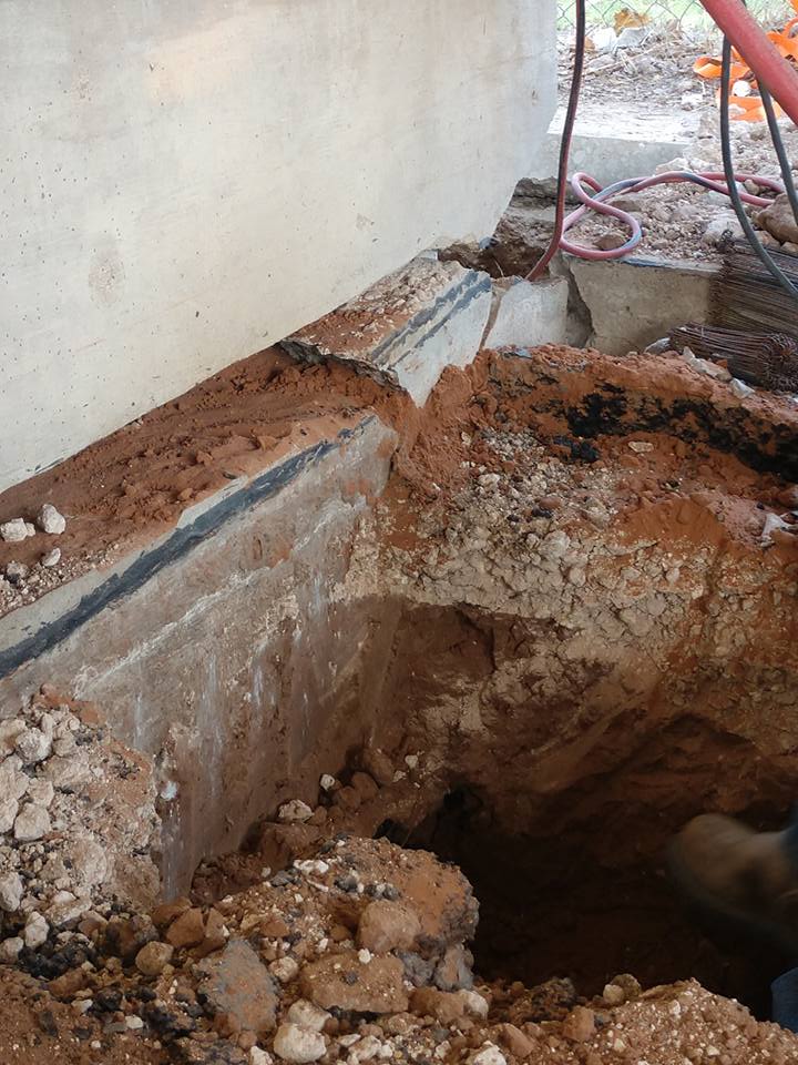 Here you can see how our crews dig beneath the grade beam. We dig beneath the grade beam and install a set of hydraulic jacks. These jacks lift the structure and help us shift the grade beam back onto the pile footings.